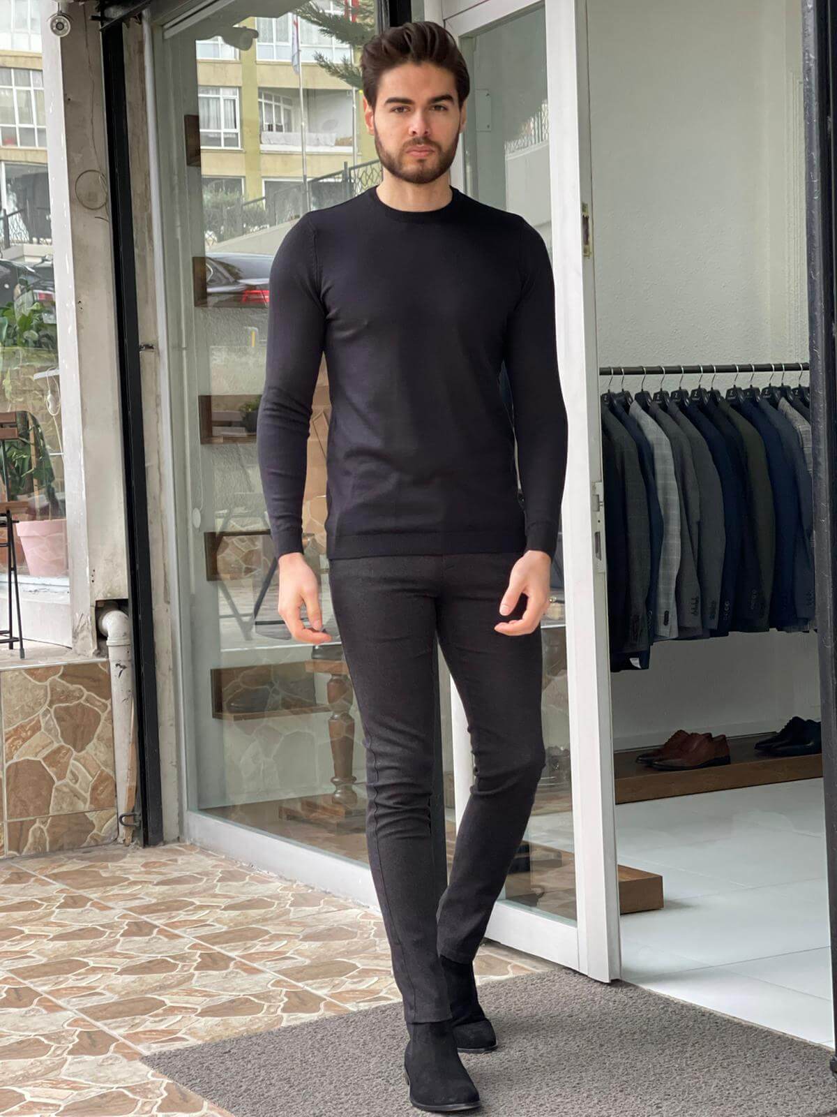 A black crewneck sweater with a relaxed fit worn by a model