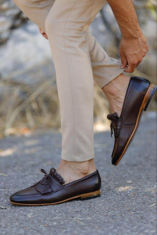 A pair of glossy brown patent leather loafers featuring custom rope detailing and neo-lite soles, blending Mediterranean flair with modern sophistication.