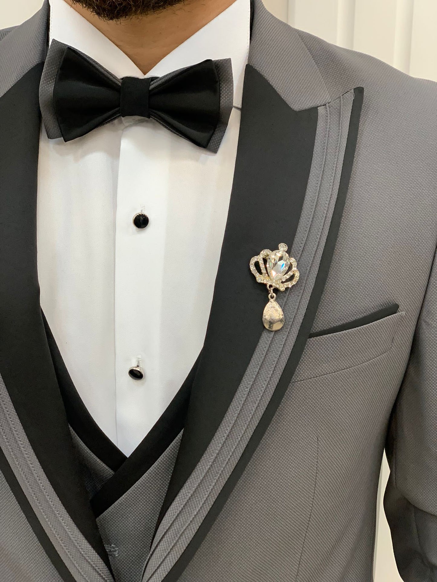 Model Wearing Gray Tuxedo with Black and Gray Patterned Peak Lapel, Single Button, Double Slit, Slim-Fit Italian Cut at a showroom