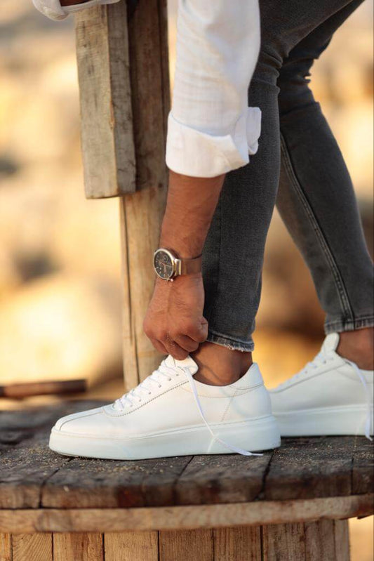 A pair of sleek white leather sneakers with a lace-up design and EVA sole, styled for warm-weather outfits and minimalist streetwear looks.