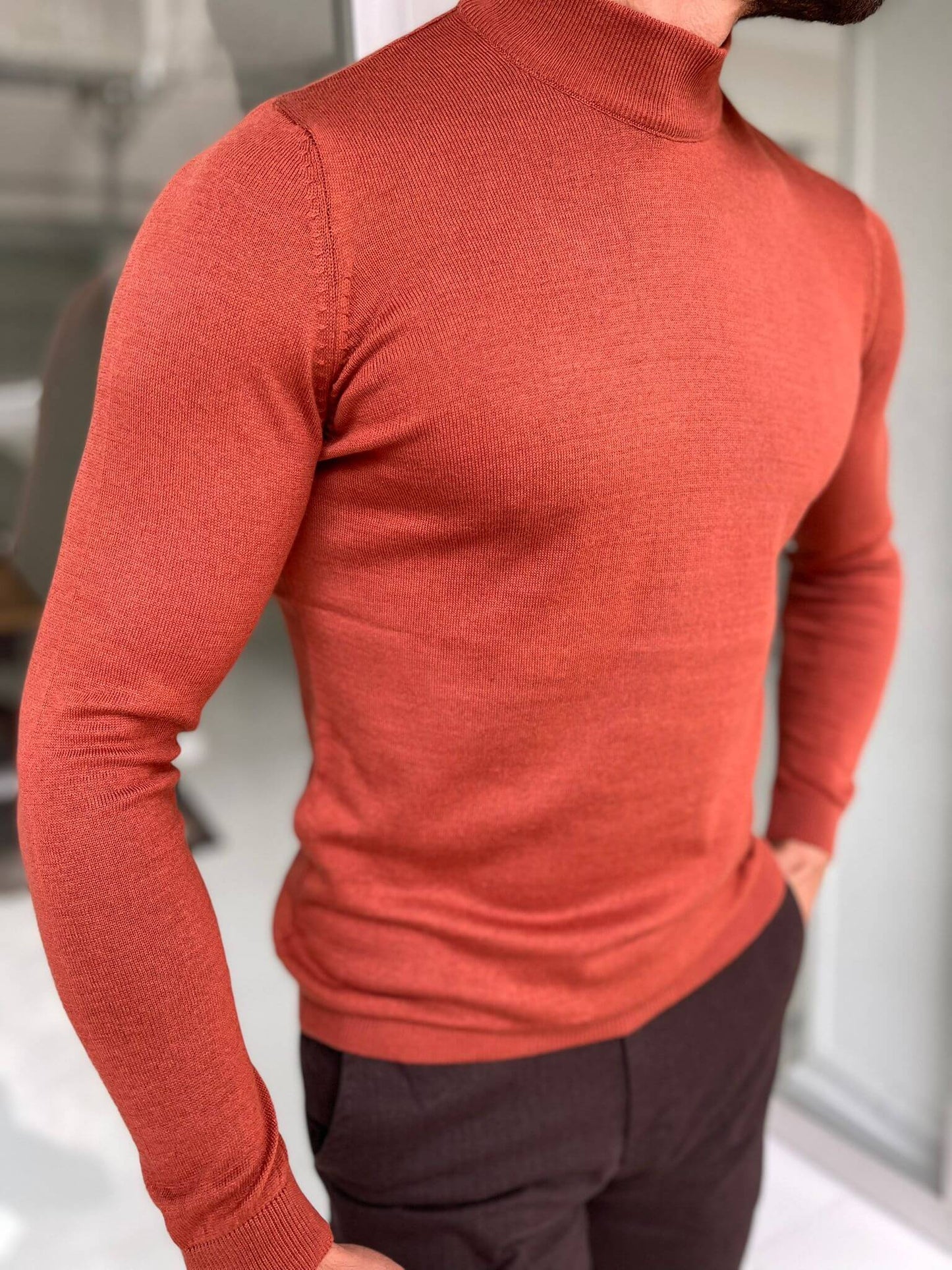 A Hollo Tile Turtlrneck sweater has a high neckline and is made from a soft, textured fabric, providing both warmth and a fashionable look."