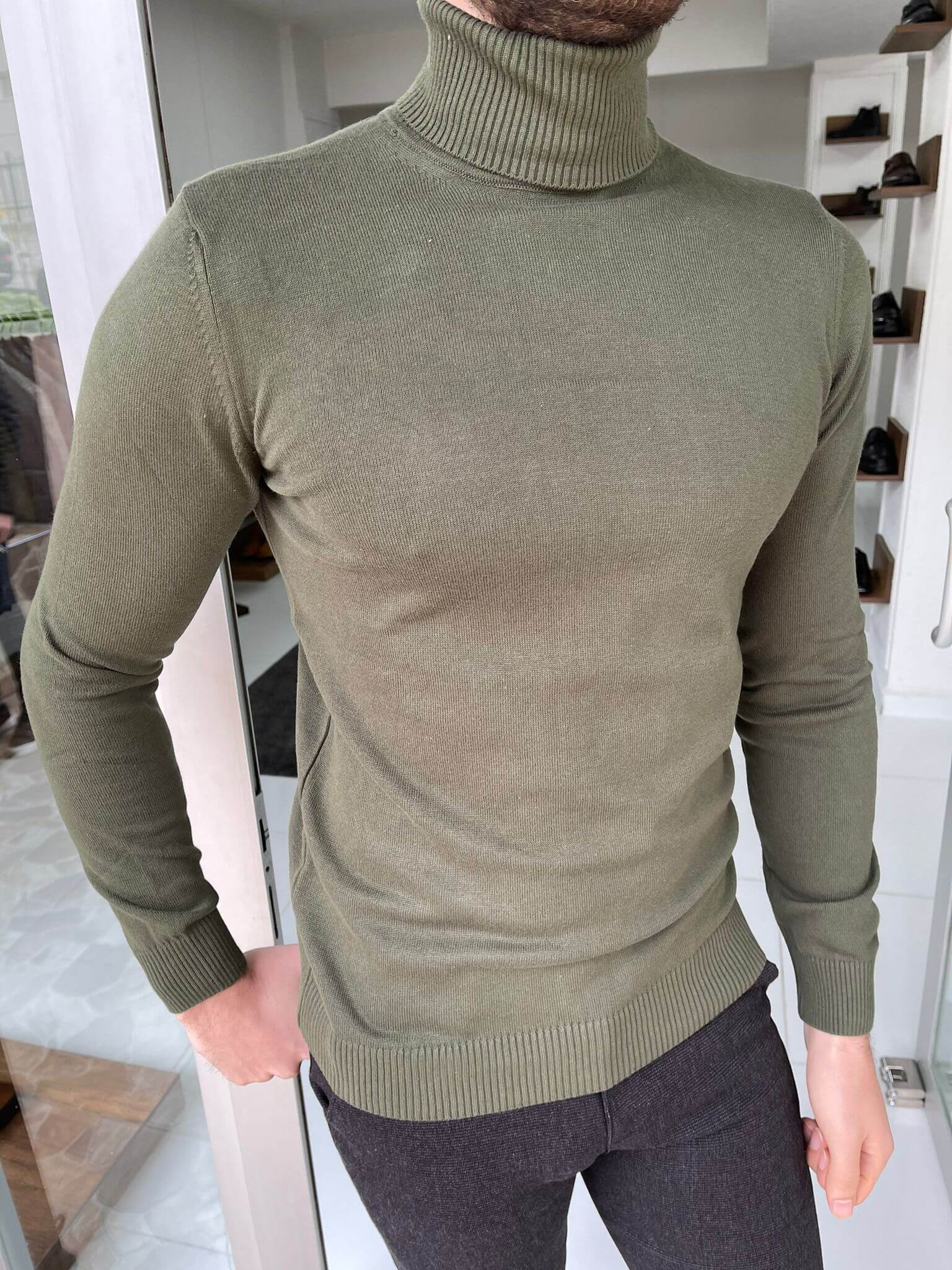 A khaki turtleneck sweater, a cozy and stylish garment with a high, folded collar, in a warm khaki color."