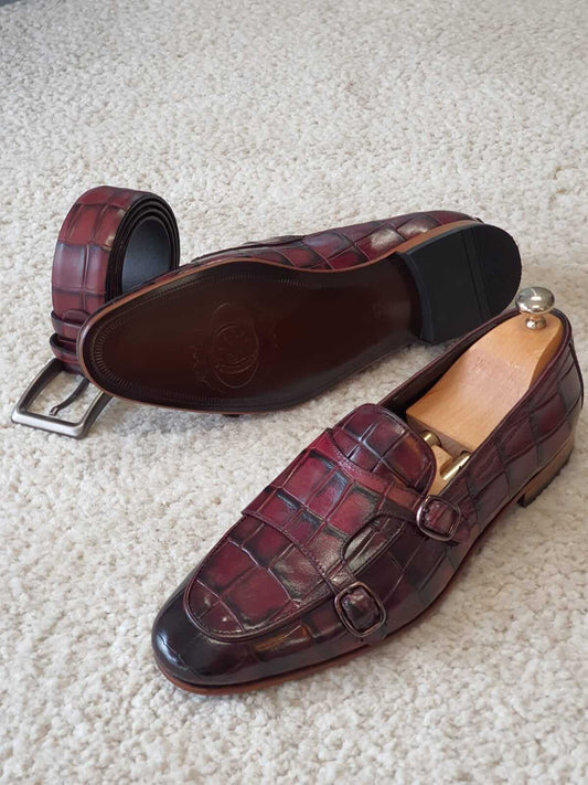 Claret red double buckle leather monk strap loafers with polished leather soles, styled for formal and smart-casual menswear settings, photographed in natural light to highlight craftsmanship.