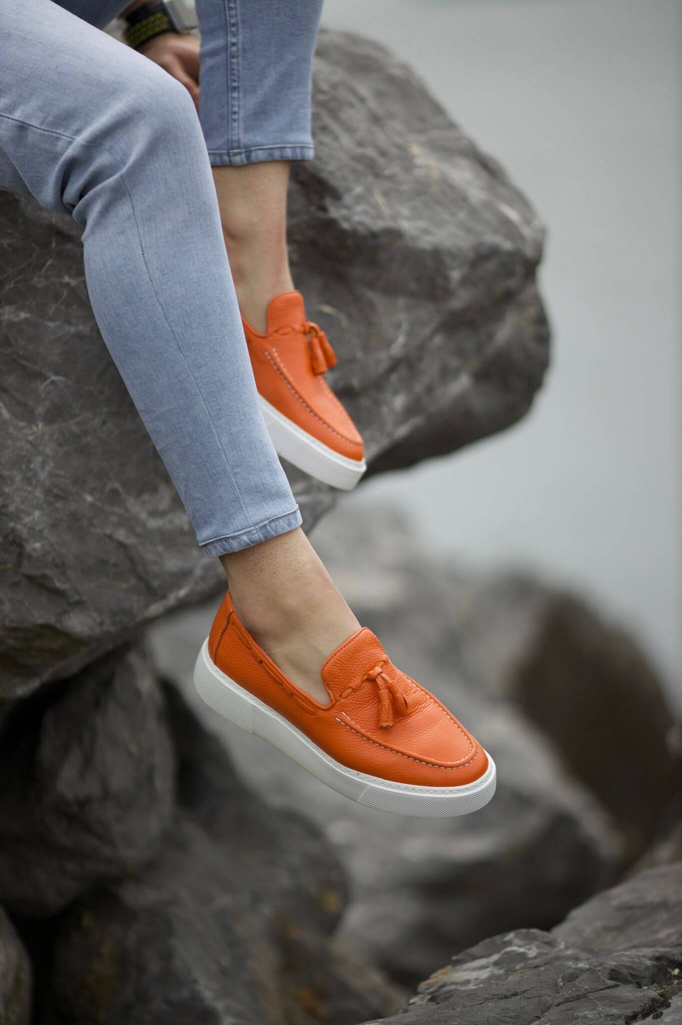 A Orange Tassel Leather Slip-Ons on display.