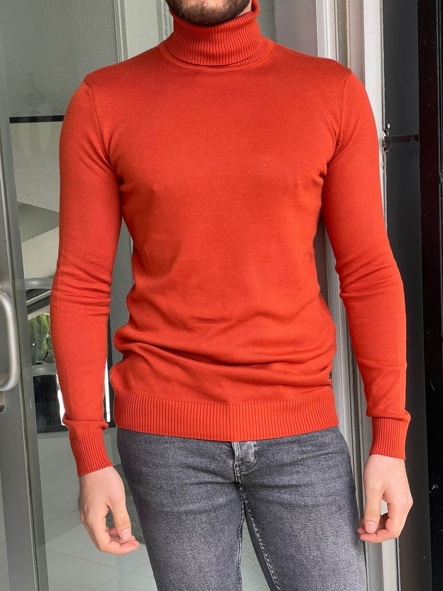 An orange turtleneck sweater, featuring a ribbed knit texture and a cozy, high neckline.