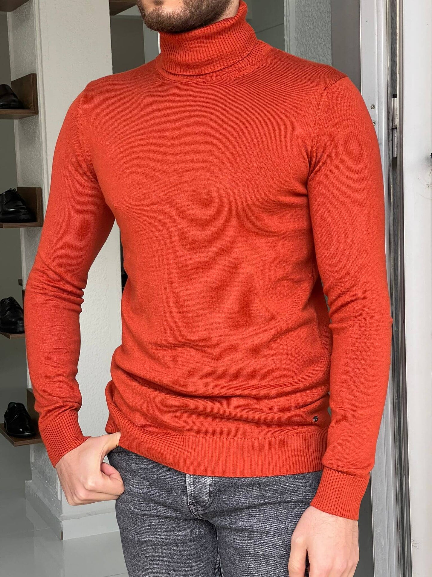 An orange turtleneck sweater, featuring a ribbed knit texture and a cozy, high neckline.