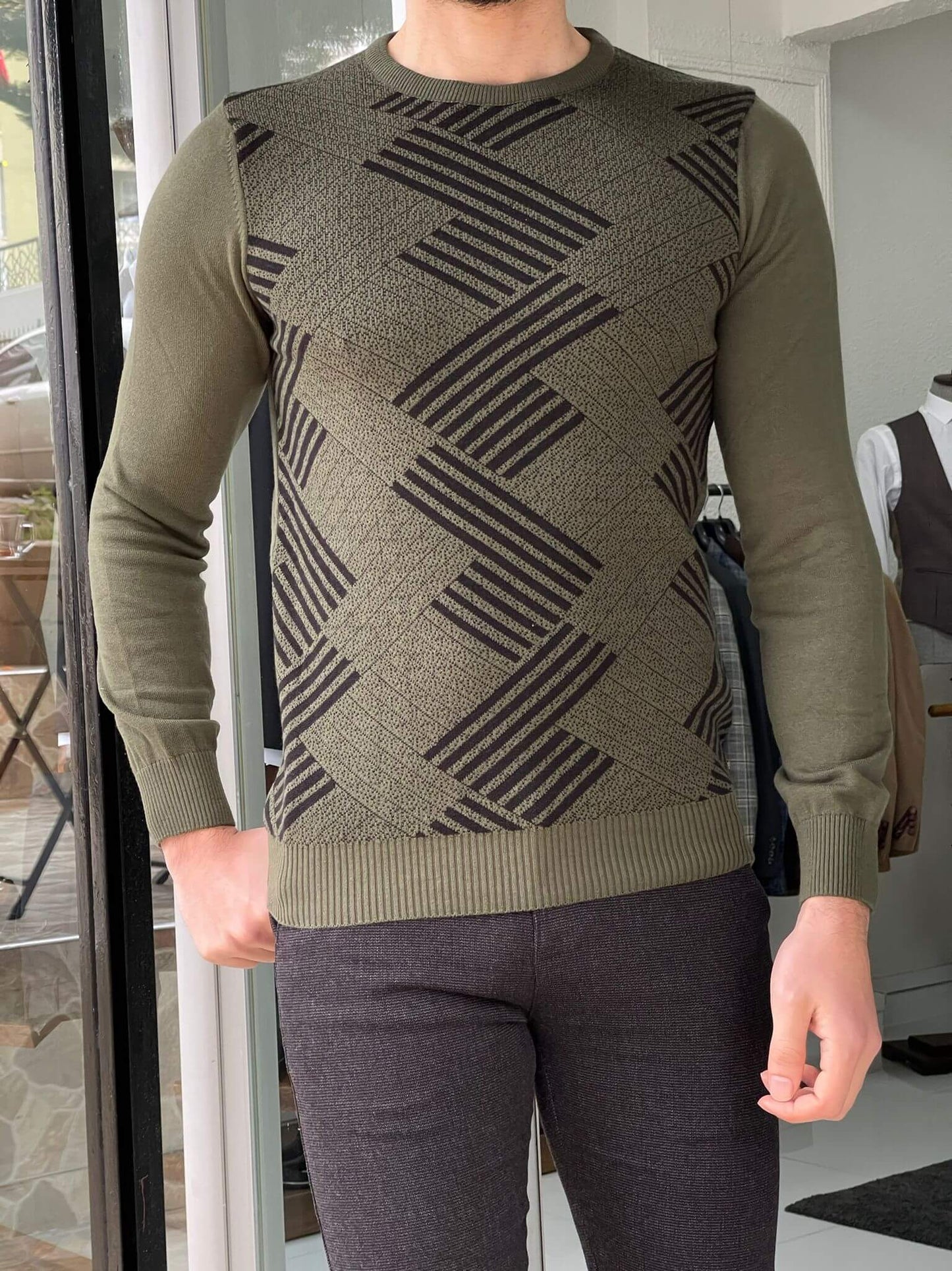A patterned khaki crewneck sweater. The sweater features a crew neckline and a khaki-colored background with intricate patterns