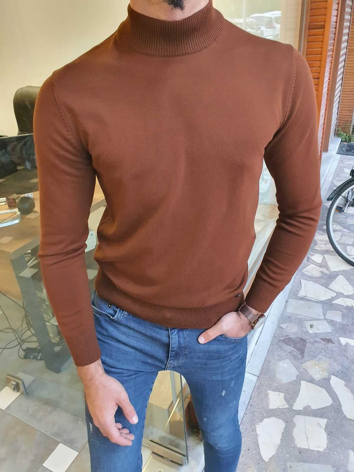A brown turtleneck sweater with a ribbed texture, featuring a high collar and long sleeves.