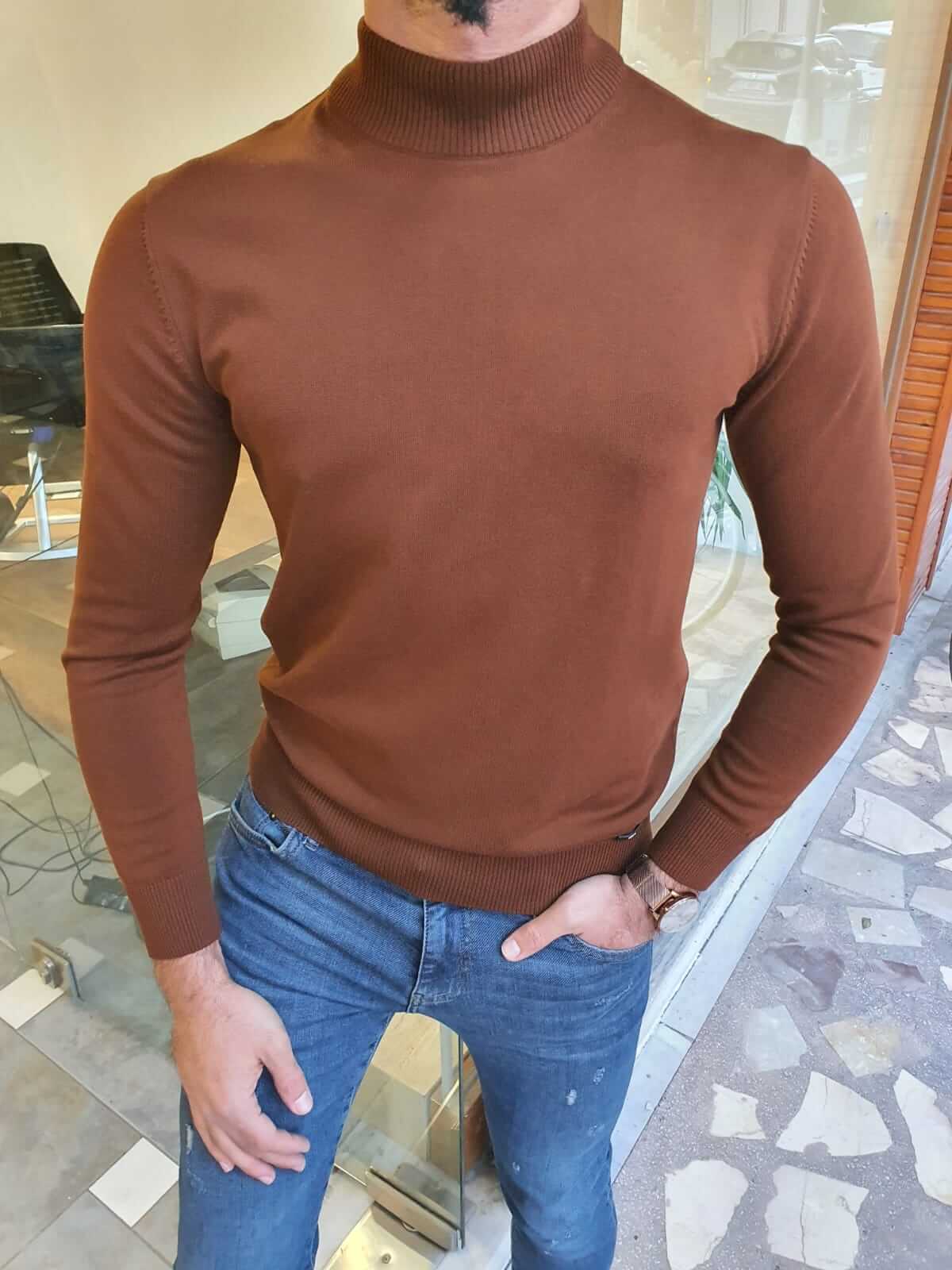 A brown turtleneck sweater with a ribbed texture, featuring a high collar and long sleeves.