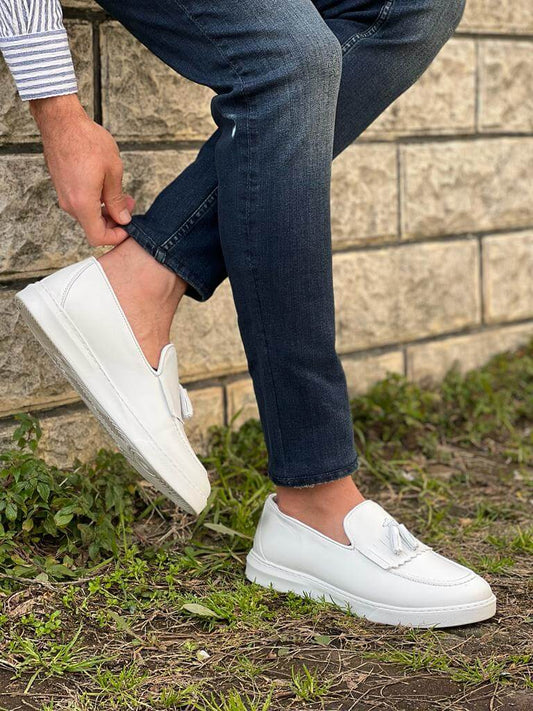 Close-up view of white tassel leather loafers with a lightweight EVA sole, photographed in bright lighting to highlight their sleek design and soft texture.
