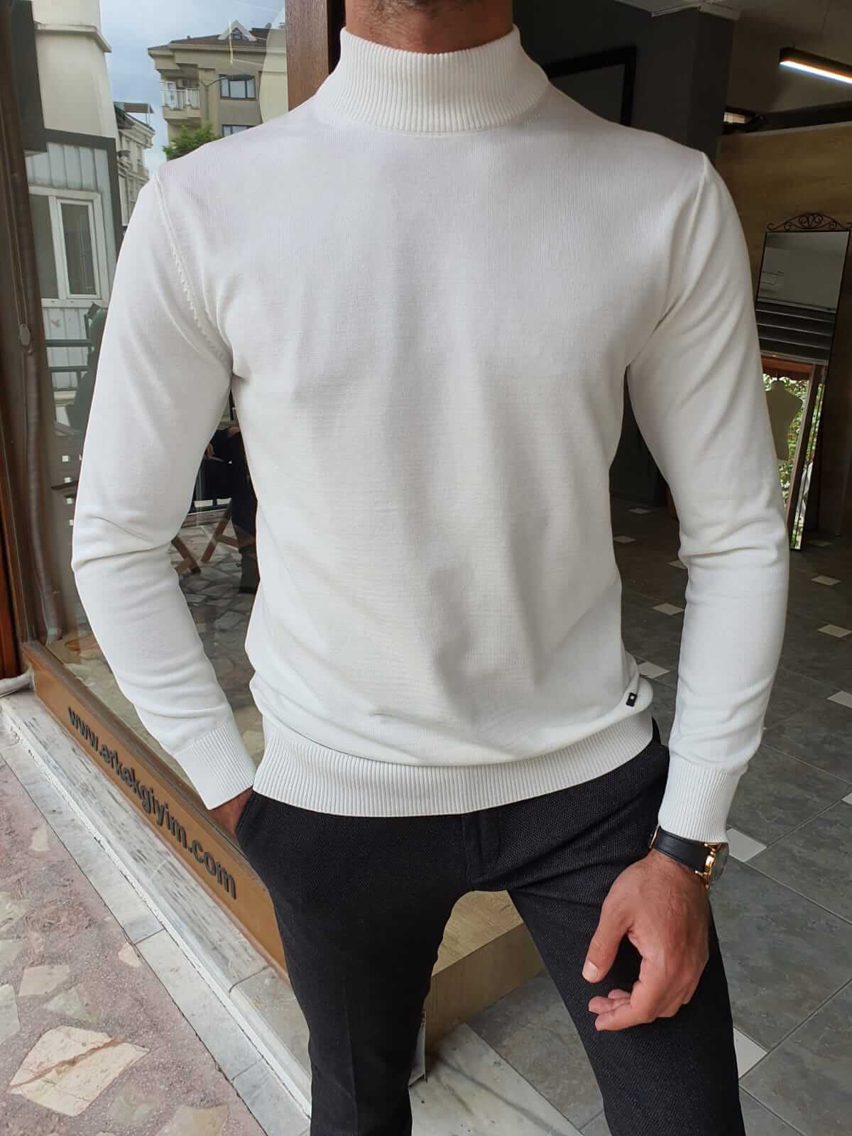 A white turtleneck sweater, neatly folded and displayed on a flat surface